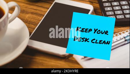 Composite of keep your desk clean text on blue sticky note with cellphone, calculator and coffee Stock Photo