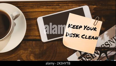 Composite of keep your desk clean on sticky note with cellphone and coffee on table Stock Photo