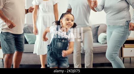 Happy girl with family dancing in living room while playing, having fun and enjoy bonding quality time together. Happy family love, connection and Stock Photo