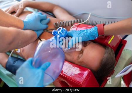 Expert paramedics carrying out CPR on the unconscious man Stock Photo