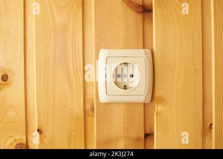 Electric socket on wooden wall, fire safety concept. Stock Photo