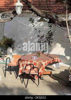 A table and two chairs placed outside in the courtyard of a house Stock Photo