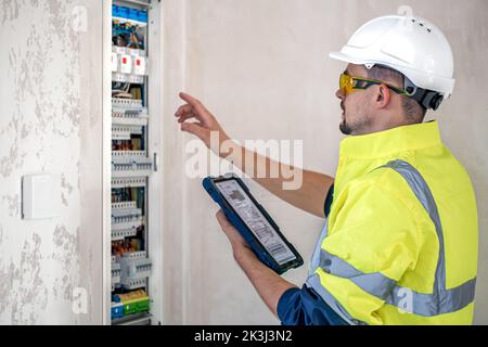 Electrical technician looking focused while working in a switchboard with fuses. Stock Photo
