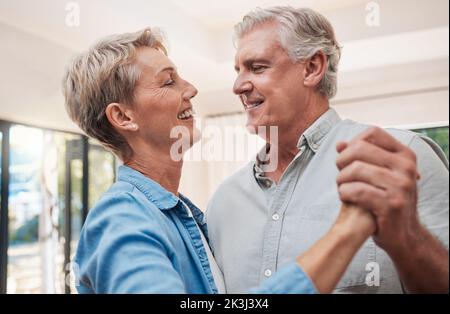 Elderly, happy and dancing couple in living room, enjoying retirement. Portrait of senior man and woman who dance together in their home, smiling Stock Photo