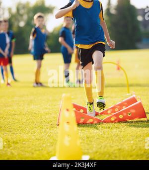 School Boy Running Slalom Track Between Training Poles and Jumping Over Cones. Teenage Football Players Running on Training Camp. Soccer Training Equi Stock Photo