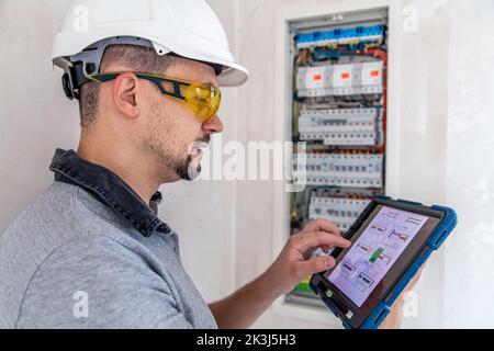 Electrical technician looking focused while working in a switchboard with fuses. Stock Photo