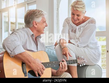 Old couple, guitar and love in home, sofa or couch playing a romantic, lovely or affection musical song for wife. Romance, retired senior man and Stock Photo