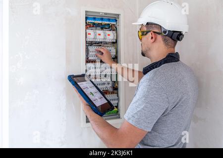 Electrical technician looking focused while working in a switchboard with fuses. Stock Photo
