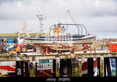 Fishing boat undergoing maintenance in the harbour at Newlyn, a small commercial fishing village in the West Country, southwest coast of Cornwall Stock Photo