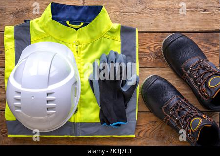 Builder uniform on wooden background, flat lay. Stock Photo