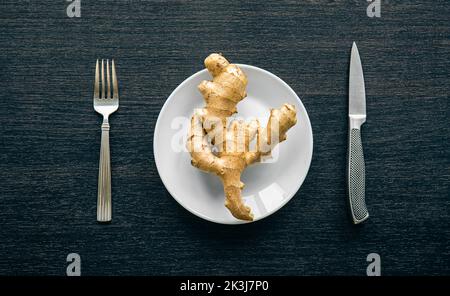 Ginger root on a plate and cutlery, conceptual minimalism, flat lay. Stock Photo