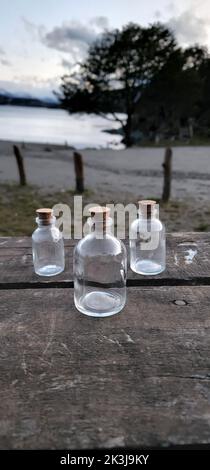 Three glass bottles with corks on the wooden table, vertical shot Stock Photo