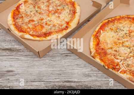 two pizzas at paper boxes. Top view of fresh baked pizza with meat and vegetables on table. delivery Stock Photo