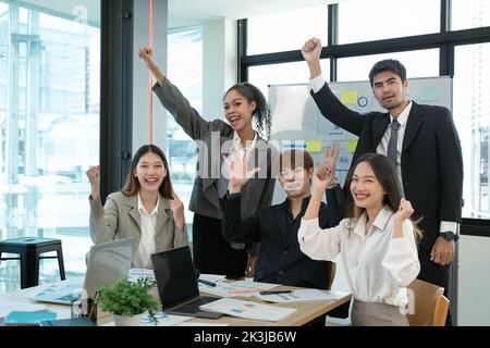 Business people smile and raise hands up, feeling happy, complete finish job, teamwork successful achievement working in office concept Stock Photo