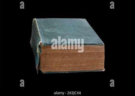 An old thick book with a green torn cover isolated on a black background with Stock Photo