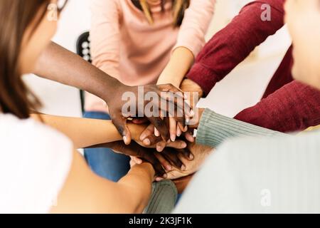 Close up high angle view of diverse young people putting their hands together Stock Photo