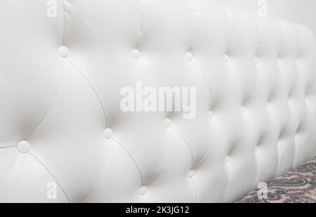 Beautiful white leather upholstery sofa with buttons. Skin texture, decorating Stock Photo