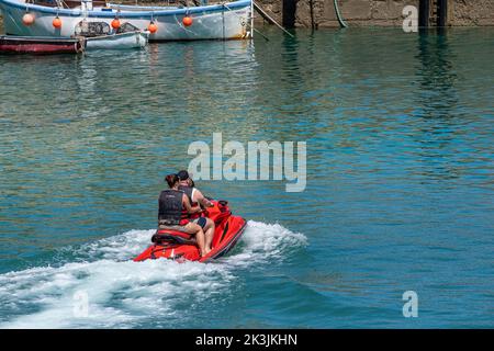 A family of holidaymakers sitting on a Kawasaki Jet Ski in Newquay Harbour Harbor in Cornwall in England in the UK. Stock Photo