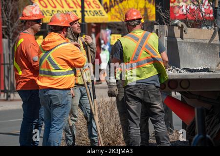 Blue collar workers at a construction site doing training. Three male employees doing road work in the streets of Toronto, Canada in 2022. Stock Photo