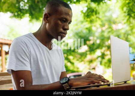 Confident, serious, calm multicultural man working online using laptop outdoors. E-learning, online internet education Stock Photo
