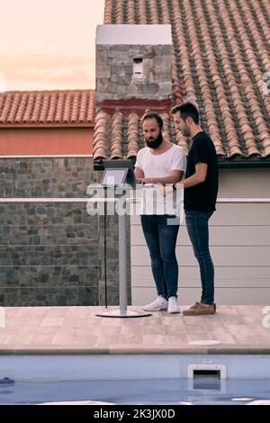 Two young entrepreneur men having a business talk while working online with their tablets at their forest home Stock Photo