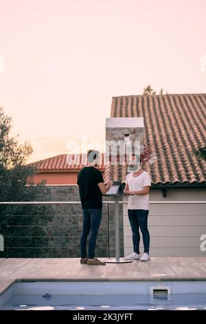 Two young entrepreneur men having a business talk while working online with their tablets at their forest home Stock Photo