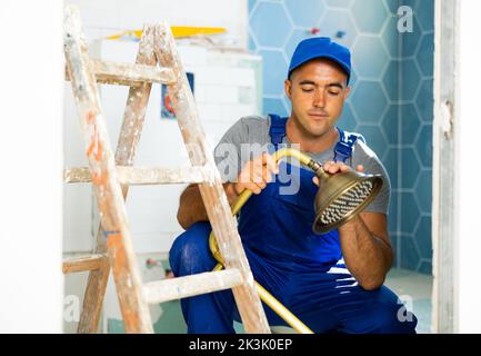 Plumbing specialist assembling tubes of shower in bathroom Stock Photo