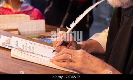 Hands writing a letter with a plume, Calligrapher writing with a vintage quill Stock Photo