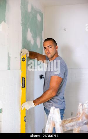 Man using spirit level on wall, working on home improvement Stock Photo