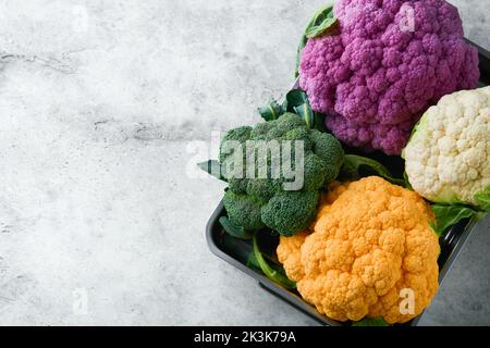 Colorfu cauliflower. Various sort of cauliflower on gray concrete background. Purple, yellow, white and green color cabbages. Broccoli and Romanesco. Stock Photo