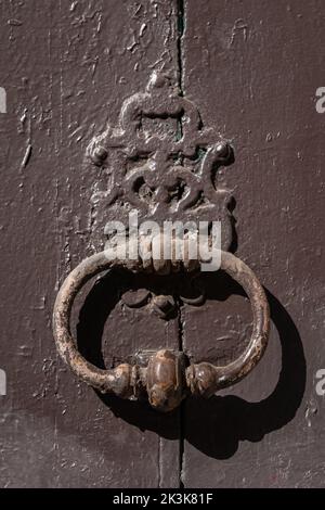 Closeup view of vintage brass door knocker isolated on ancient brown wooden door, Montpellier, France Stock Photo
