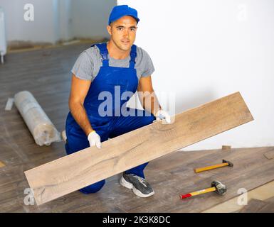 Worker laying wooden parquet floor during renovation Stock Photo