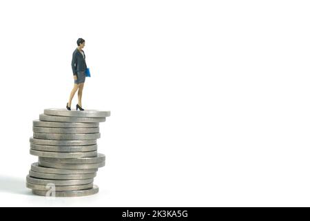 Miniature people toy figure photography. Salary growth concept. Businesswoman standing above coin pile. Isolated on white background Stock Photo