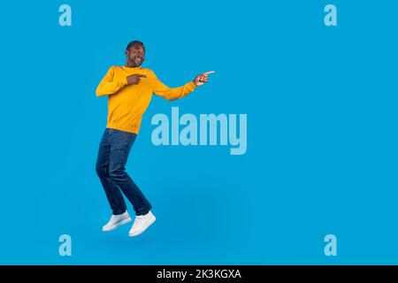 Excited african american man jumping and pointing at copy space Stock Photo