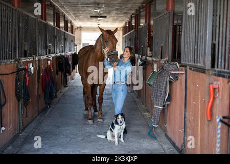 Young woman in a stable with her horse Stock Photo