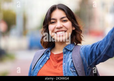 Cheerful Young Middle Eastern Woman Taking Selfie Outdoors On City Street Stock Photo