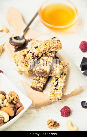 Various homemade granola bars with nuts, seeds, dark chocolate, honey and berries over a wooden board. Stock Photo