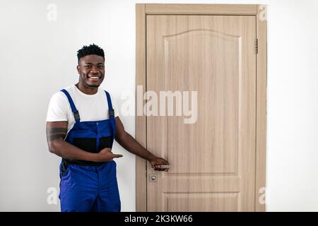 Black Male Worker Pointing At New Door After Installation Indoors Stock Photo