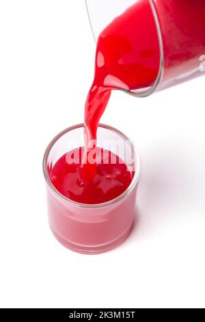 red color drink or juice pouring into glass, close-up of beverage isolated on white background Stock Photo