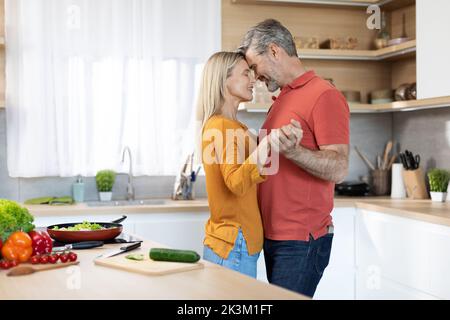 Romantic middle aged couple having fun at kitchen, dancing Stock Photo