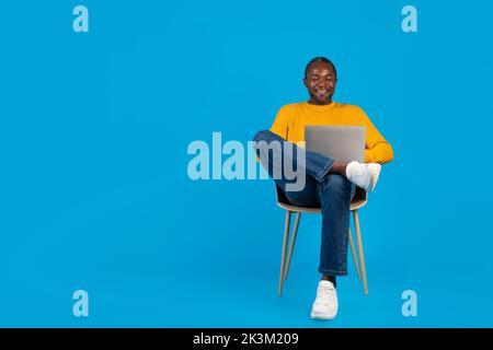 Handsome black man relaxing on chair with computer Stock Photo