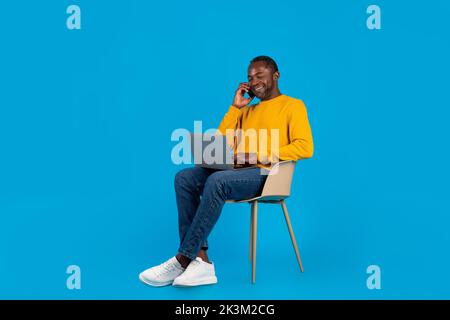African american man freelancer working on laptop, having phone call Stock Photo