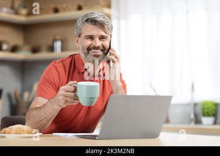 Cheerful handsome man drinking coffee and having conversation Stock Photo