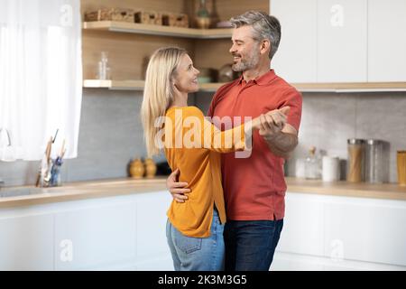 Beautiful mature spouses dancing together at kitchen Stock Photo