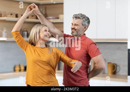 Loving middle aged couple dancing at kitchen Stock Photo