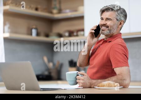 Attractive middle aged entrepreneur working from home, having phone call Stock Photo