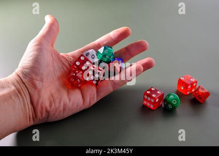 Man's hand picking up different dice to throw them. Stock Photo