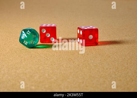 Two transparent red six dice and one green twenty dice reflecting light on the table. Stock Photo