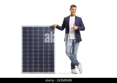 Young man leaning on a solar panel and pointing isolated on white background Stock Photo