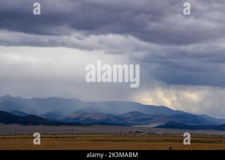 Storm clouds drop rain over the distant mountains in the high desert near Moffat in Colorado USA Stock Photo